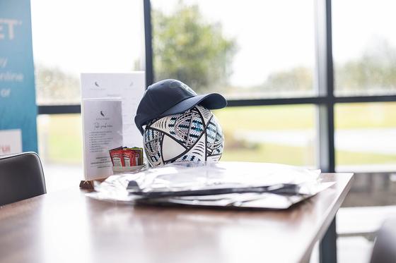 A Stroke Play Golf cap resting on a football on a clubhouse table