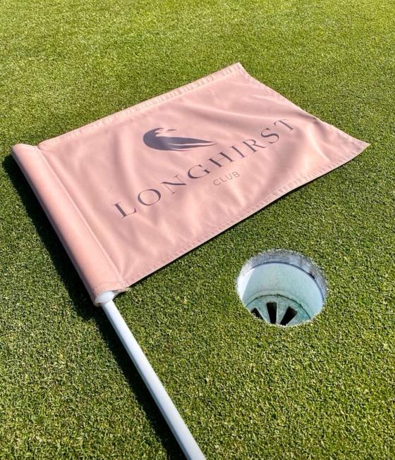A Longhirst Club pin flag lying beside the hole